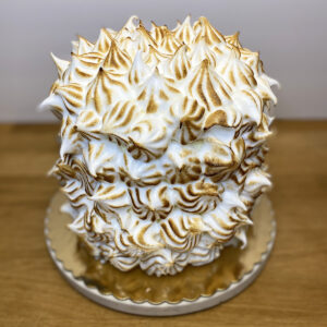 A cake with white frosting and brown swirls on top.