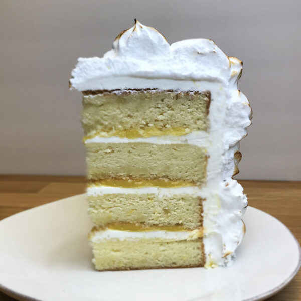 A white cake with whipped cream on top sitting on a plate.