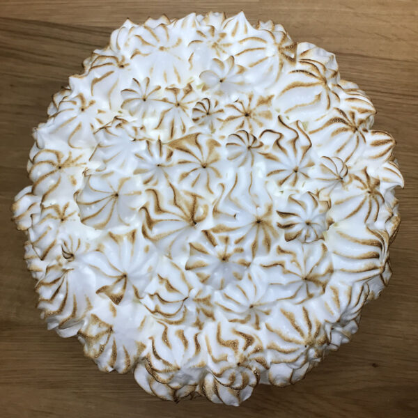 A cake with white frosting and brown swirls on top.