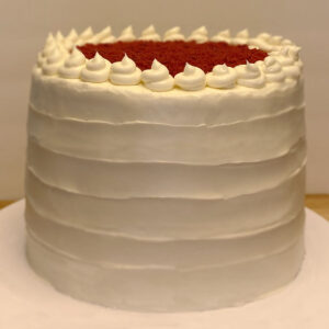 A white cake with red and white frosting on top.