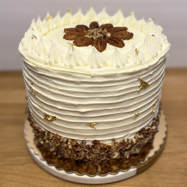 A white cake with brown frosting and gold sprinkles.