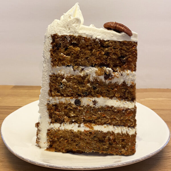 A carrot cake with white frosting on top of a plate.