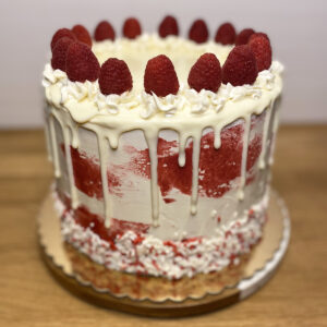 A cake with white frosting and red strawberries.