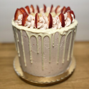 A cake with white frosting and strawberries on top.