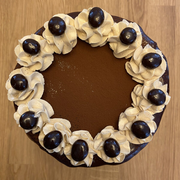 A chocolate cake with white frosting and black berries.